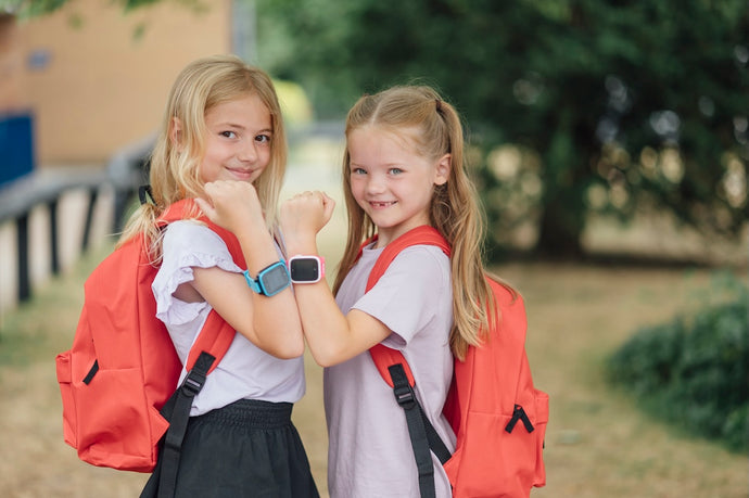 2 børn i skole med et blå og lyserødt XGo3 Smartwatch til børn med GPS og ringefunktion.