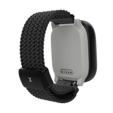 Xplora X6Play i sort set bagfra. Fokus på den magnetiske opladningsport og det elastiske flettede armbånd med sort X-spænde. Fremviser det smarte og komfortable design til børn.