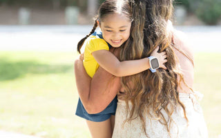 Datter krammer mor efter hun er kommet hjem fra skole med hendes smartwatch til børn fra Xplora med GPS tracking og trygge zoner.