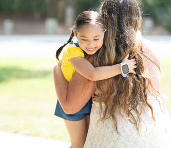 Datter krammer mor efter hun er kommet hjem fra skole med hendes smartwatch til børn fra Xplora med GPS tracking og trygge zoner.