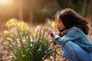 Barn dufter til en blomst med et GPS smartwatch til børn i naturen. 