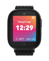 Xplora X6Play i sort med farverig startskærm, der viser tid, dato, vejr og skridttæller. Skærmen viser tirsdag den 7. september kl. 12:29.