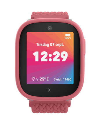 Xplora X6Play i lyserød med en farverig startskærm. Viser dato, tid, vejrinformation og barnets skridttælling i en legende brugerflade.
