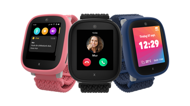 Tre Xplora X6Play smartwatches til børn vises i forskellige farver – pink, sort og blå. Skærmene viser funktioner som sms'er fra forældre, indgående opkald fra "mor" og en hovedskærm med tid, dato, vejr og skridttæller. Urene har farverige skærme og tekstilremme, hvilket giver en sikker og børnevenlig kommunikationsoplevelse.